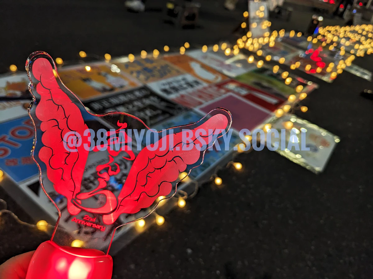 赤く光るゑんらのペンライトを手前に、地面に並べられたプラカードの列を奥に捉えた写真。プラカードの周囲にはガーランドライトが張り巡らされている。