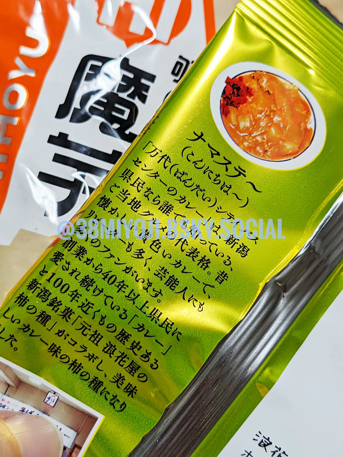 柿の種パッケージの裏面。カレーライスの写真と、「ナマステ〜（こんにちは〜）」という見出し、さらにバスセンターカレーの由緒や柿の種になった経緯などが簡単に説明されている。